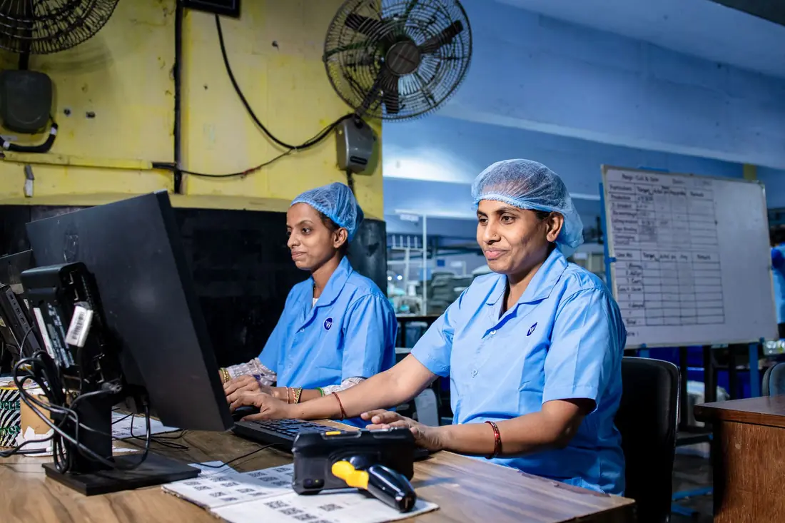 Women plant staff in uniforms working at computers on a factory office floor