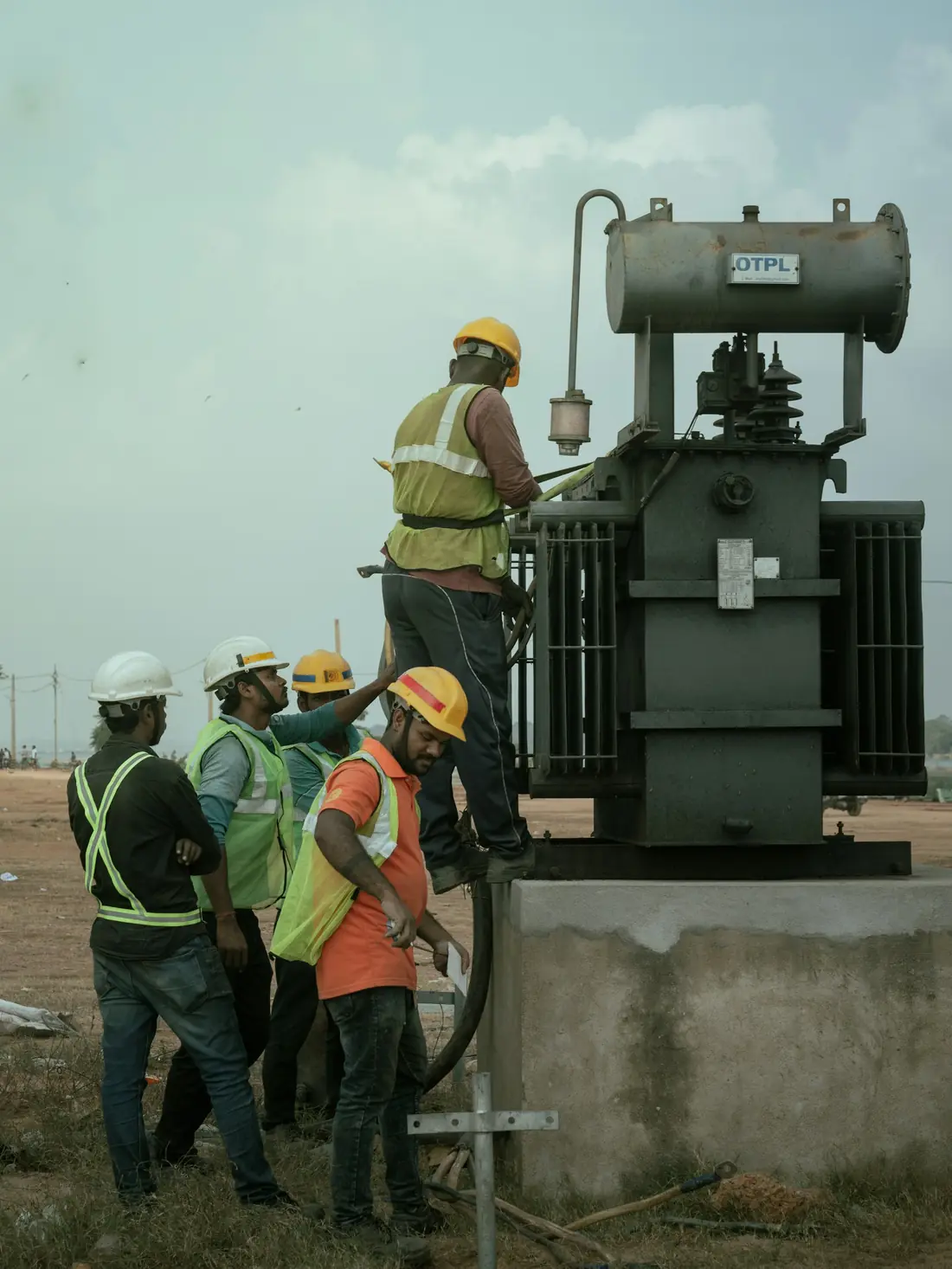 Engineers in hard hats inspecting electrical equipment at an industrial site