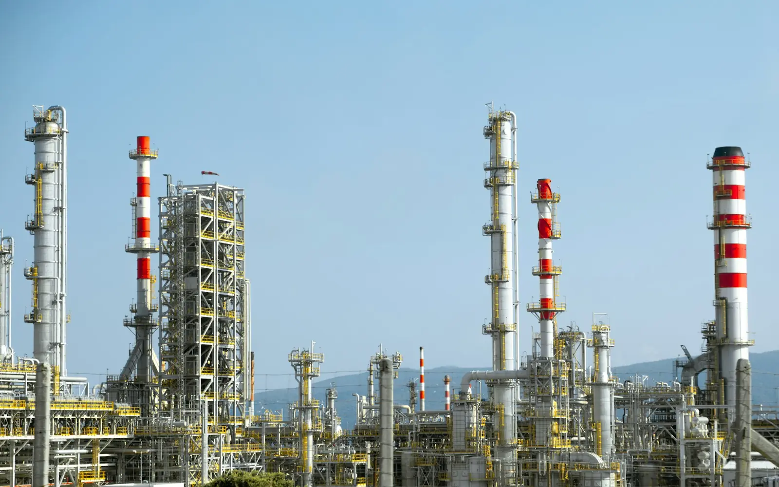 A chemical processing plant with columns and pipework under a clear sky